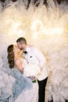 bride and groom kiss in front of the feather wall with neon sign at JW Marriott Marquis Miami wedding