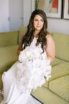 bride with loose curls and hoop earrings with large white orchid bouquet