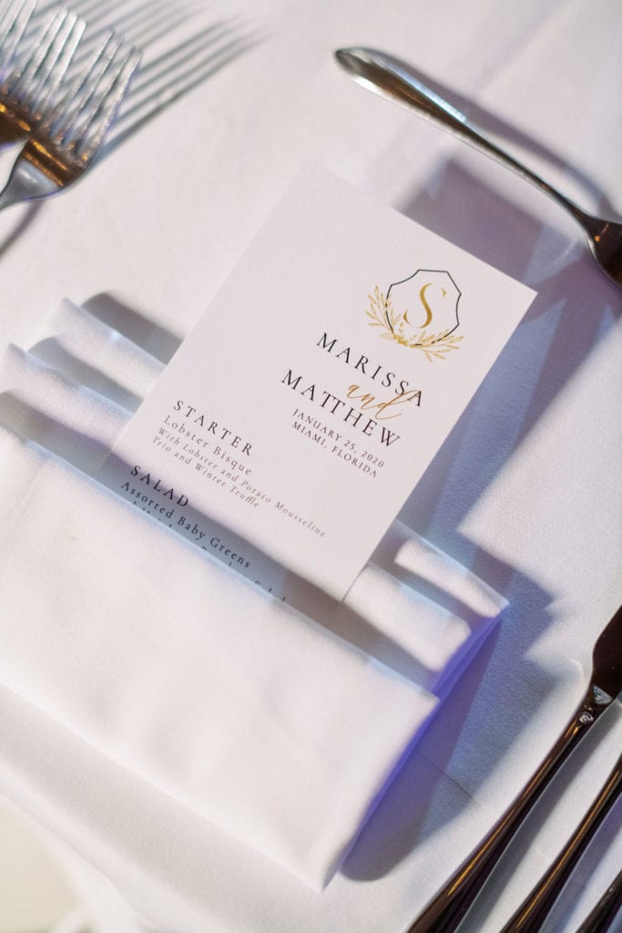 White dinner menu card in between a white linen table napkin at The Mandarin Oriental, wedding planned by Oh My Occasions