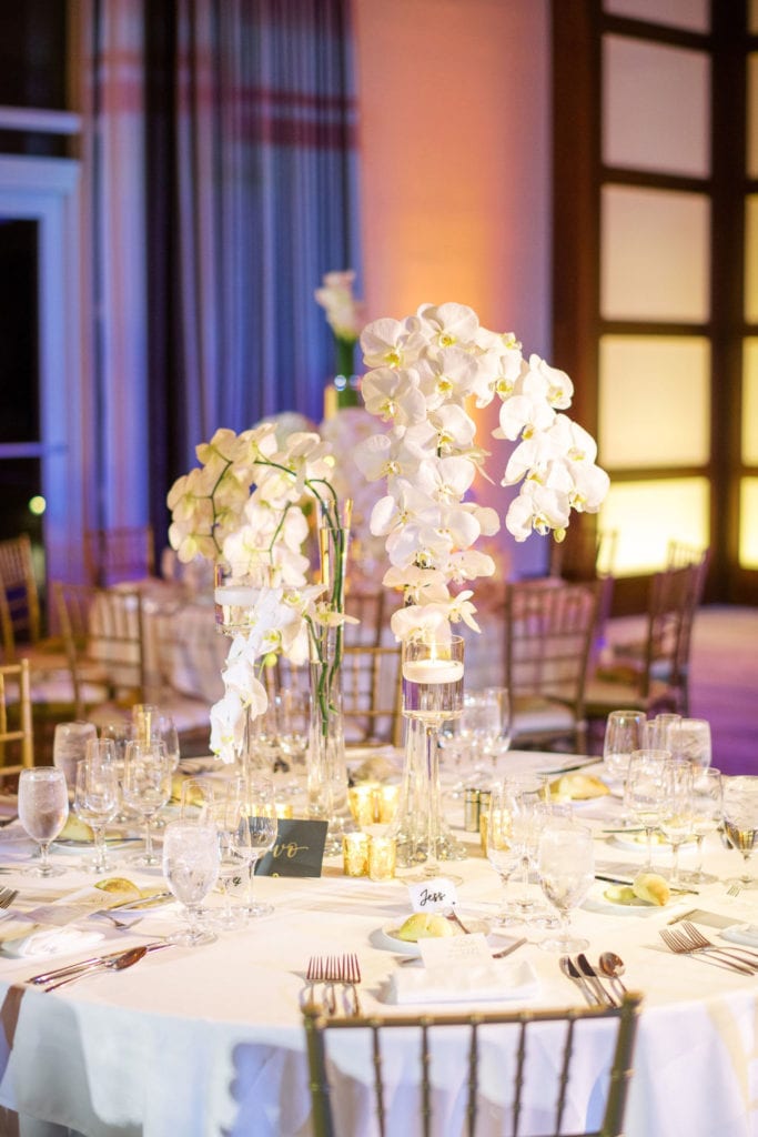 Beautiful reception table with white table linen with a floral centerpiece made of orchids and hydrangeas at The Mandarin Oriental, wedding planned by Oh My Occasions