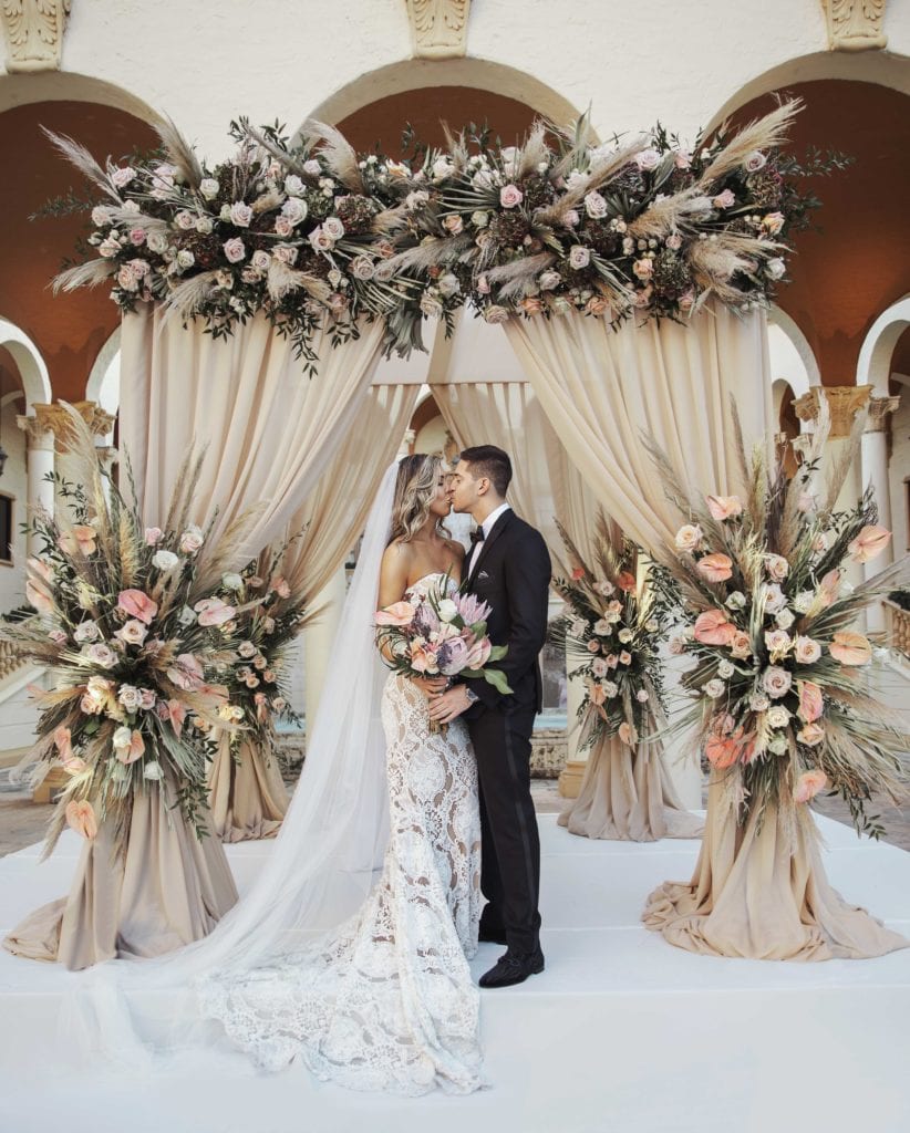 Bride and groom kiss under the chuppah at The Baltimore Hotel in Miami Coral Gables, wedding planned by Oh My Occasions