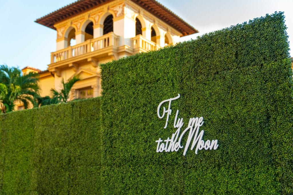 Grass wall with phrase Fly me to the Moon as the ceremony entrance closeup at The Baltimore Hotel in Miami Coral Gables, wedding planned by Oh My Occasions