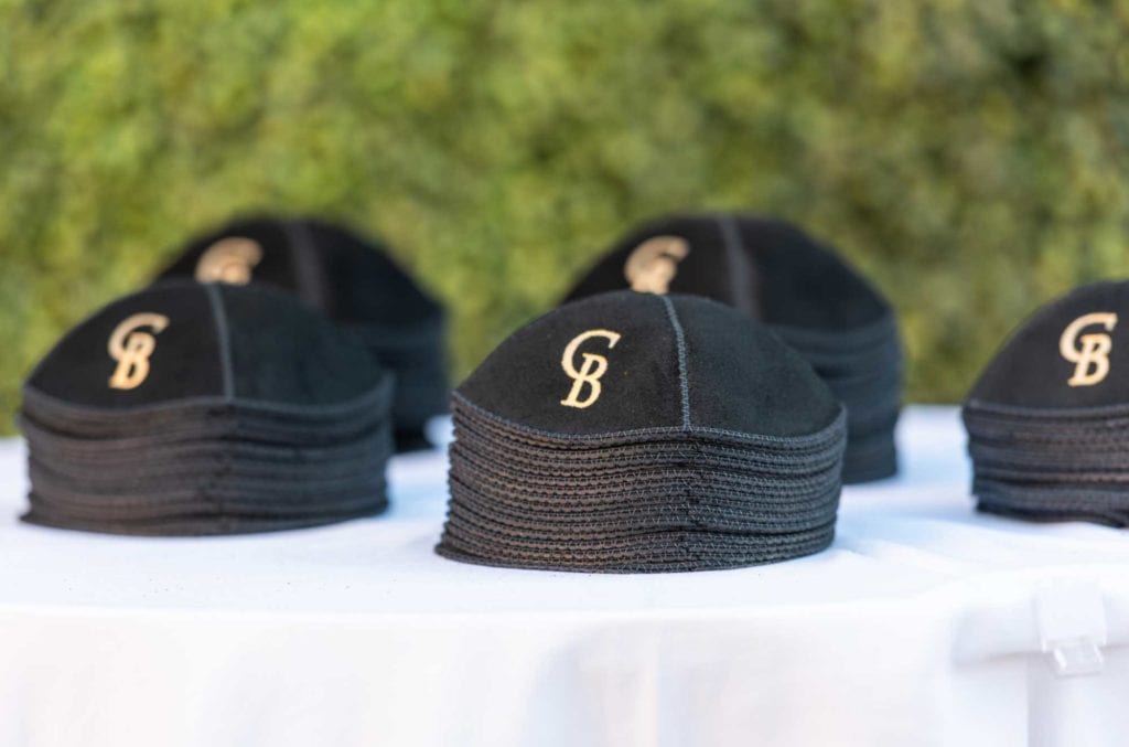 Black kippahs with couples initials on top of white tablecloth for the ceremony at The Baltimore Hotel in Miami Coral Gables, wedding planned by Oh My Occasions