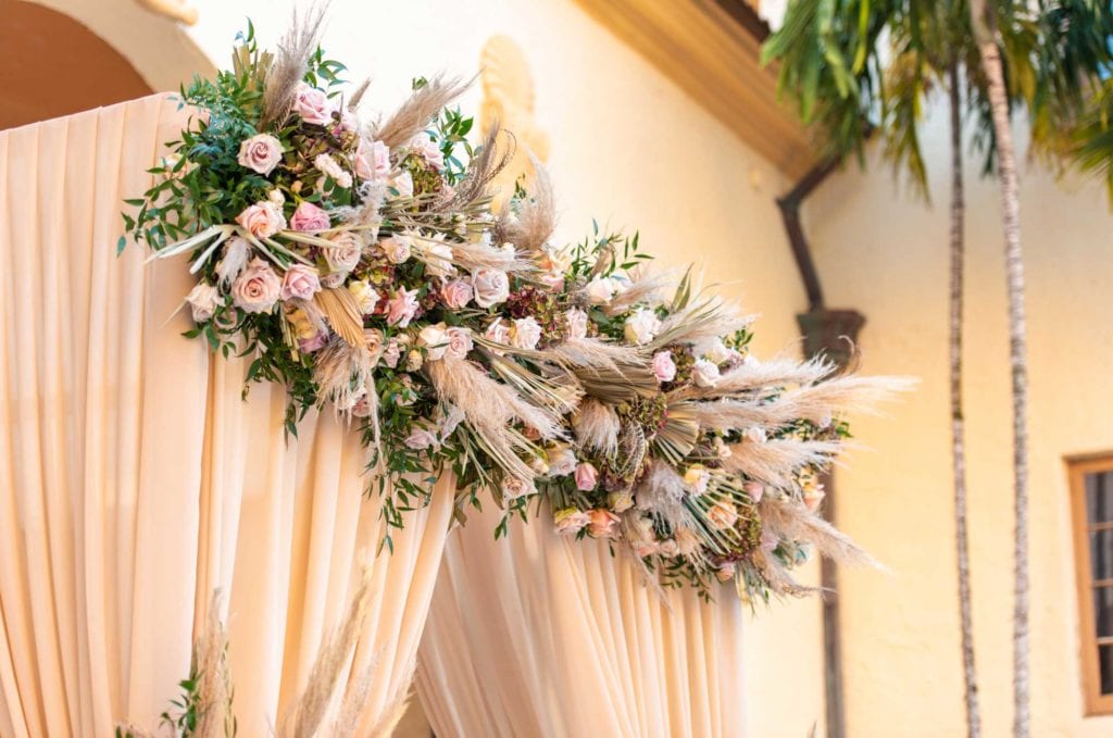 Outdoor ceremony chuppah with pampas grass and champagne draping