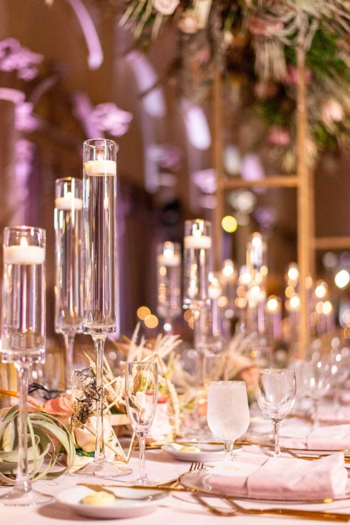 Closeup of table scape with candles and flowers in the middle.