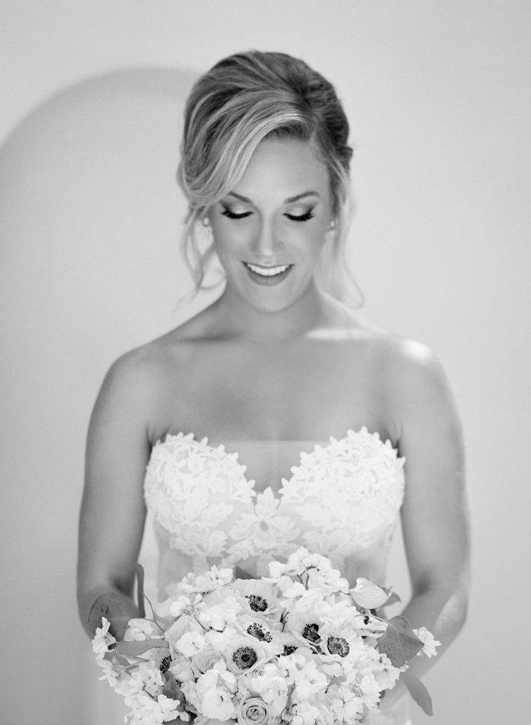 black and white photo of bride smiling down at her bouquet