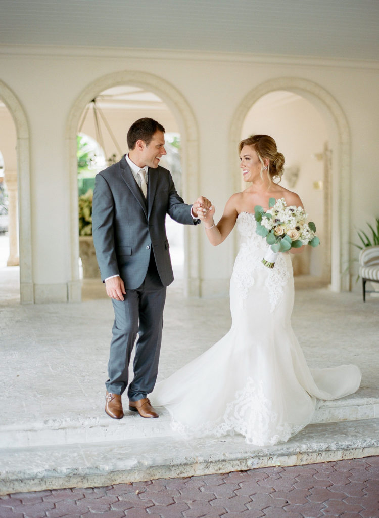 Couple walk towards photographer smiling at each other for their first looks at the Fisher Island Club.