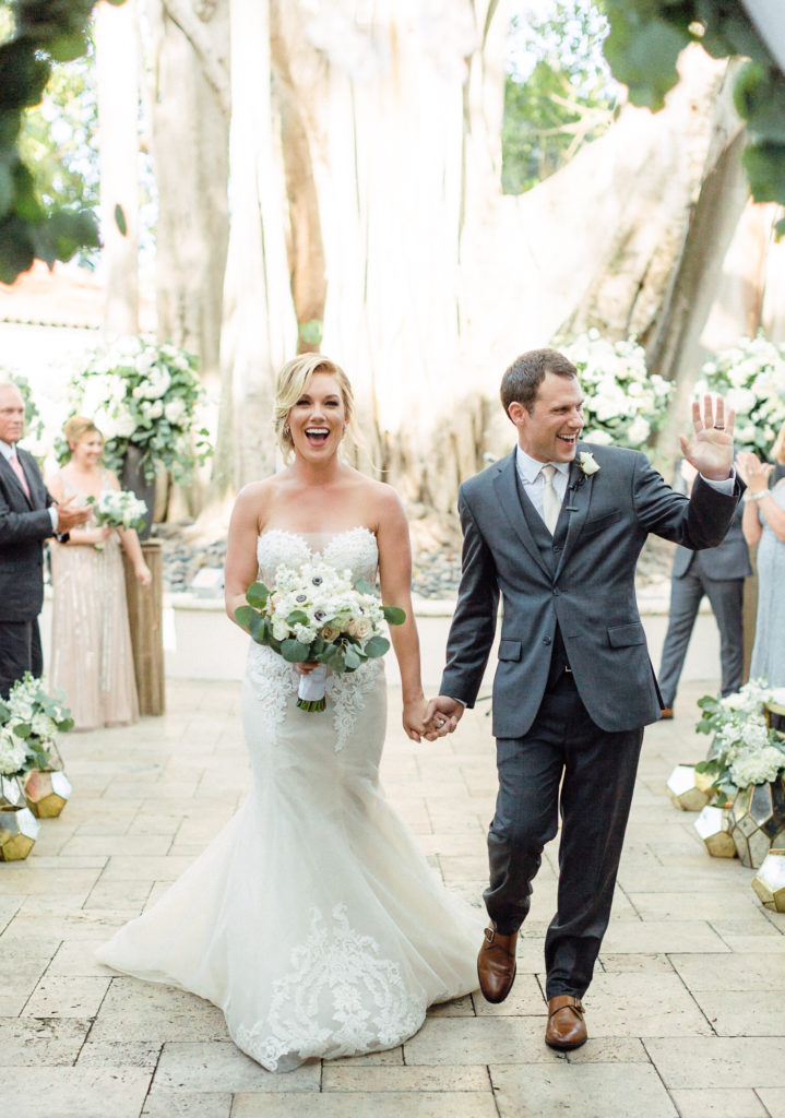 Newlywed couple walk down the aisle in their outdoor ceremony space.
