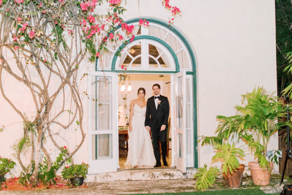 The bride and groom coming out of the circle doors at Villa Woodbine in Coconut Grove, wedding planned by Oh My Occasions