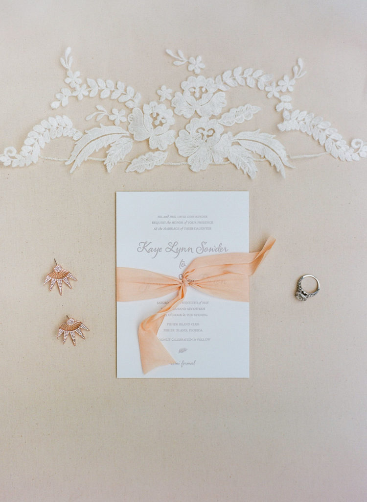 Wedding invitation with blush ribbon, earrings and ring.
