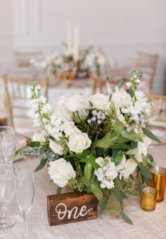 Floral centerpiece with white roses and table sign at The Club of Knights, wedding planned by Oh My Occasions