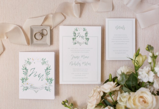 Wedding invitation layout with white roses, wedding rings, and ribbons at The Club of Knights, wedding planned by Oh My Occasions