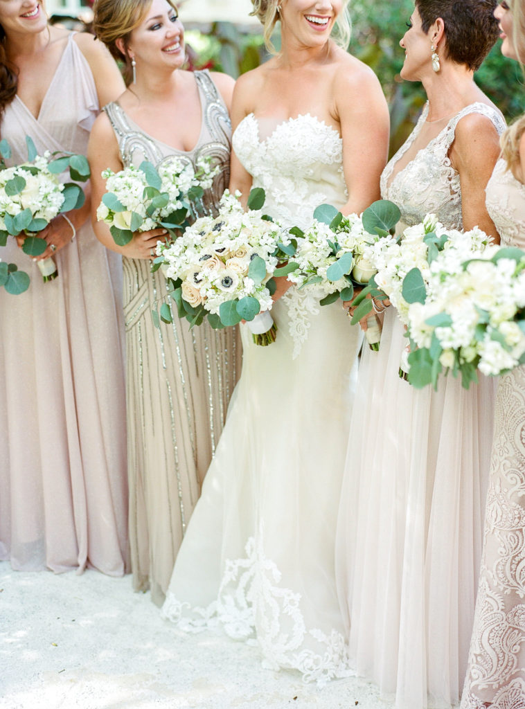 A closeup of the bouquets as the bride and bridal party stand outside and smile at each other.