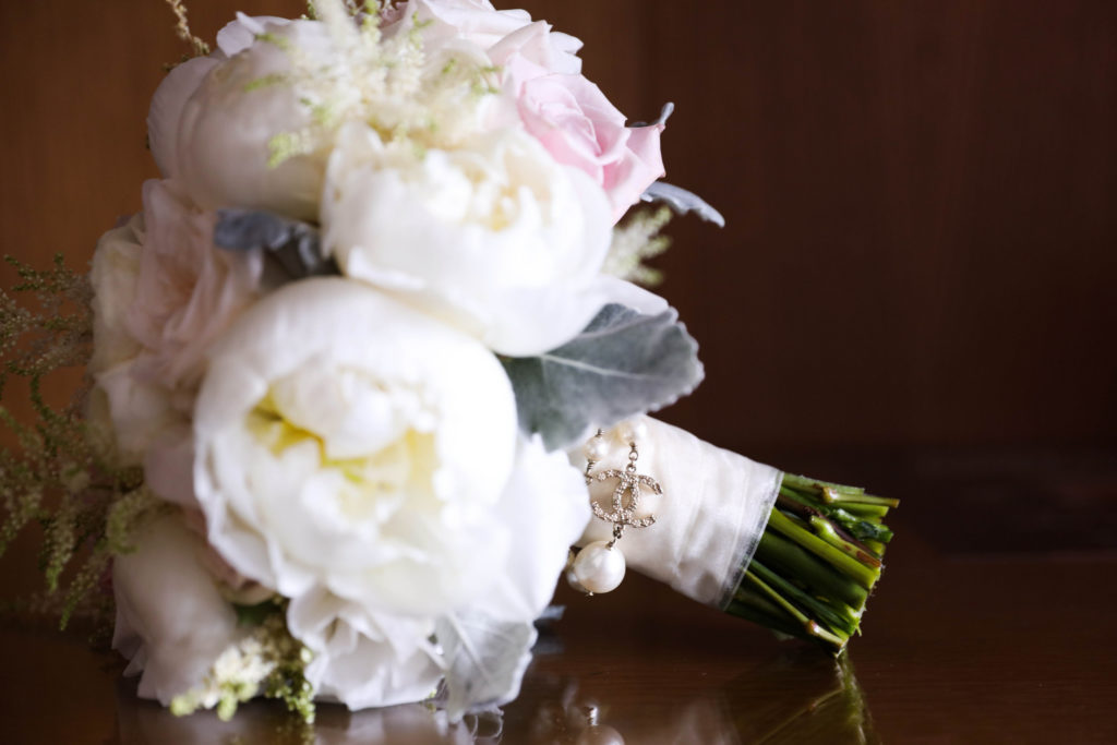 White and pink rose flower bouquet with a channel bouquet charm at the Kimpton EPIC Hotel, planned by Oh My Occasions