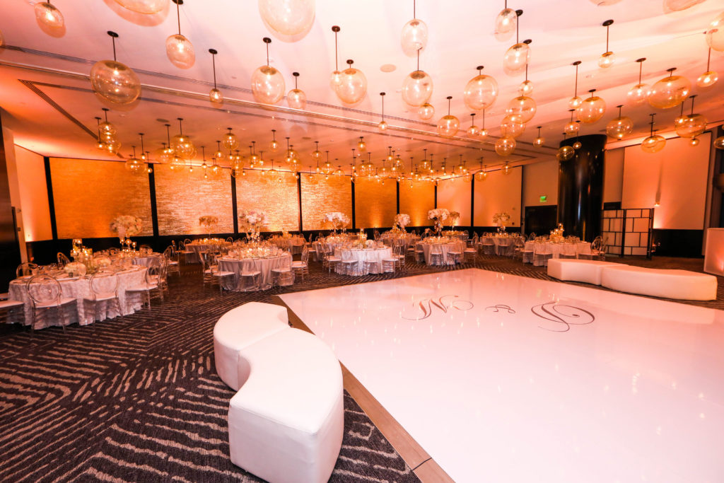A beautiful overview of the reception ballroom with a lounge setup, wrapped dance floor, and acrylic mirror accents at the Kimpton EPIC Hotel, planned by Oh My Occasions