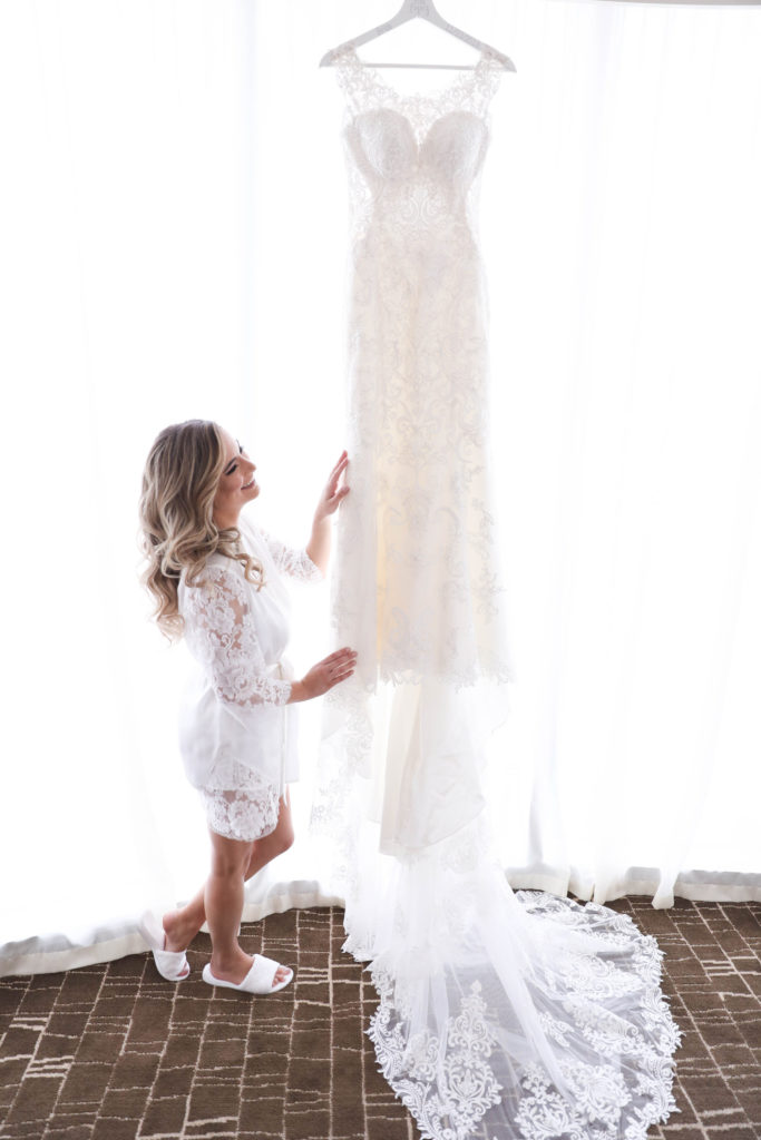 The bride admiring her beautifully hung wedding dress at the Kimpton EPIC Hotel, planned by Oh My Occasions