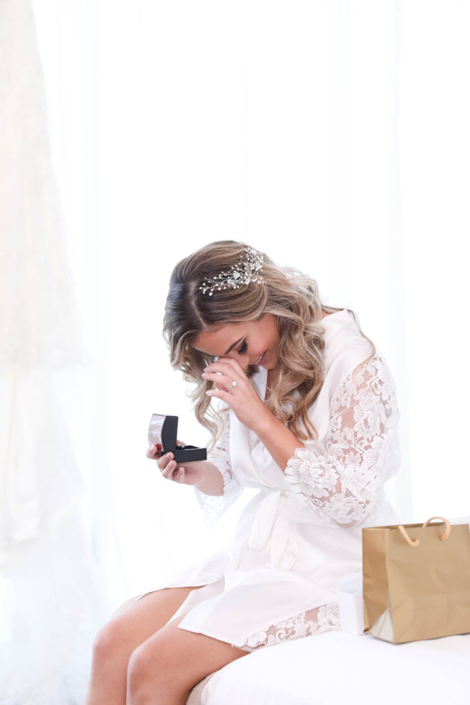 The bride getting ready  in her robe admiring the wedding rings at the Kimpton EPIC Hotel, planned by Oh My Occasions