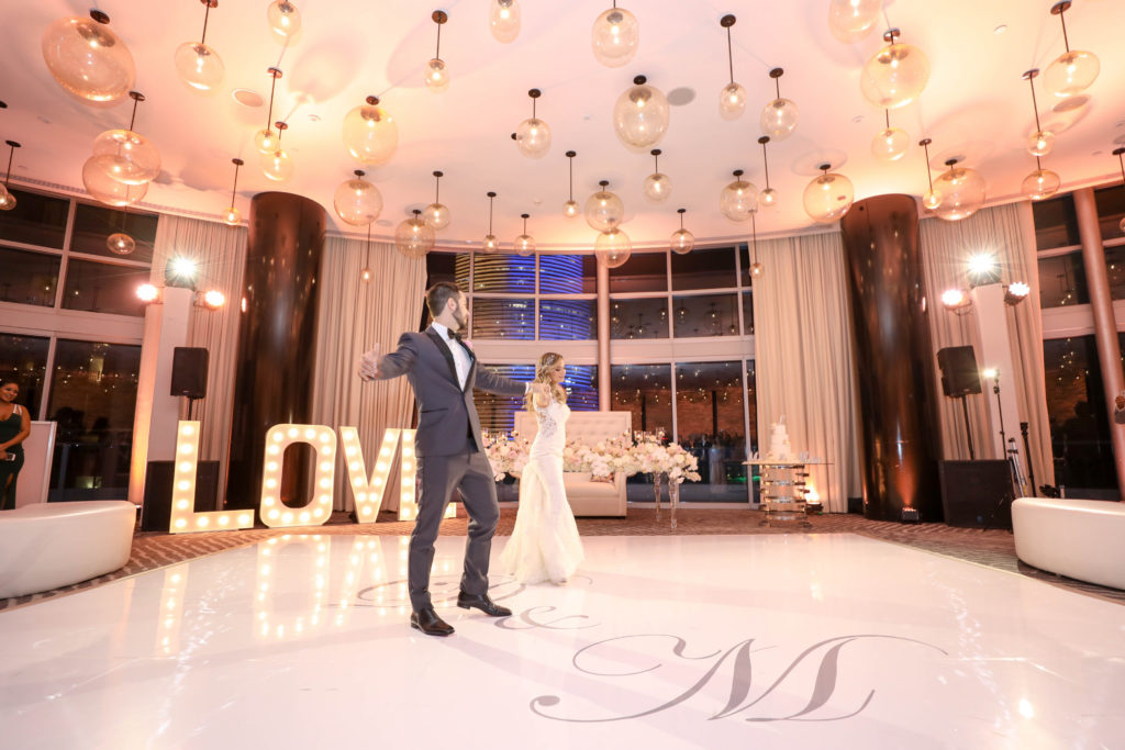 The bride and groom dancing on their custom wrapped floor at the Kimpton EPIC Hotel, planned by Oh My Occasions