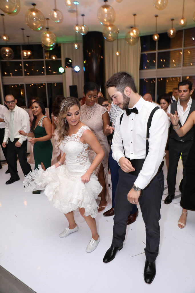 The bride and groom busting out dance moves on their custom wrapped dance floor at the Kimpton EPIC Hotel, planned by Oh My Occasions
