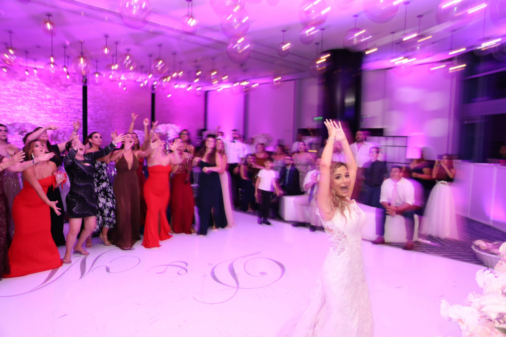 The bride on the dance floor throwing her bouquet to the crowd at the Kimpton EPIC Hotel, planned by Oh My Occasions