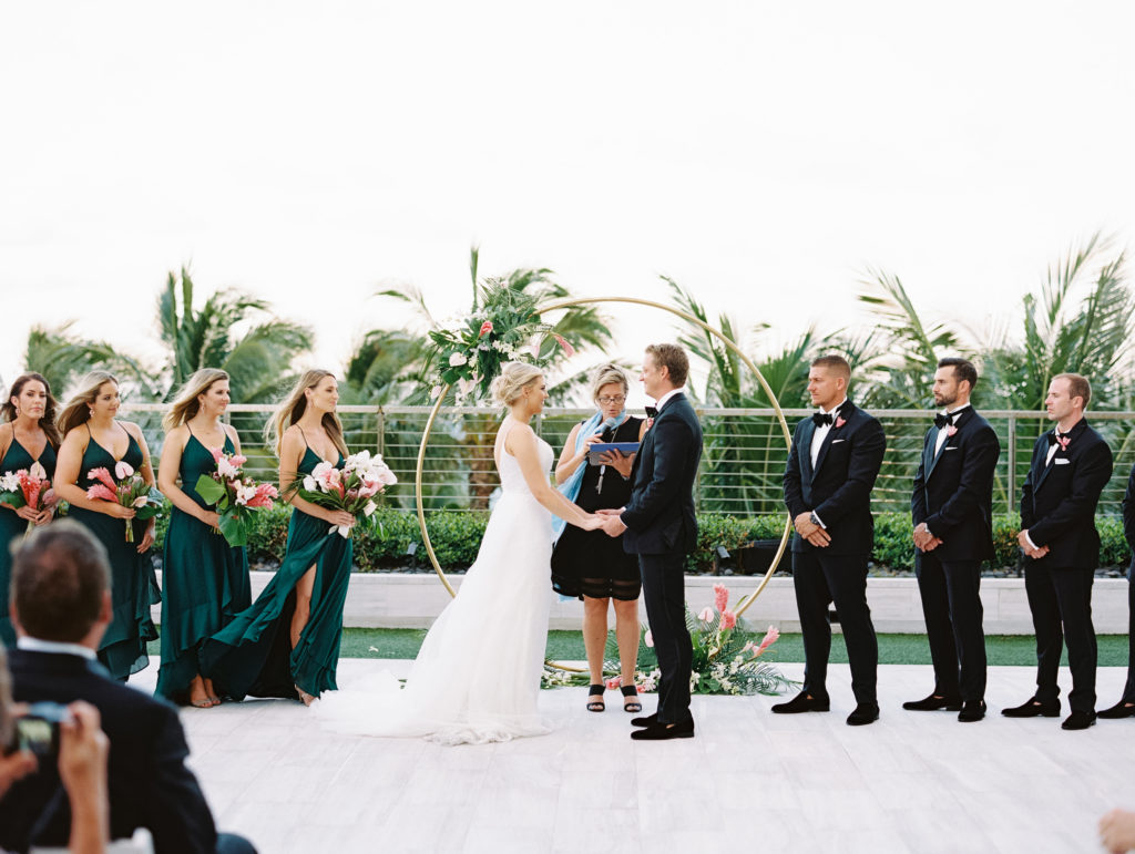 The bride and groom with their bridesmaids and groomsmen standing at the alter outdoors at Miami Beach Edition, planned by Oh My Occasions
