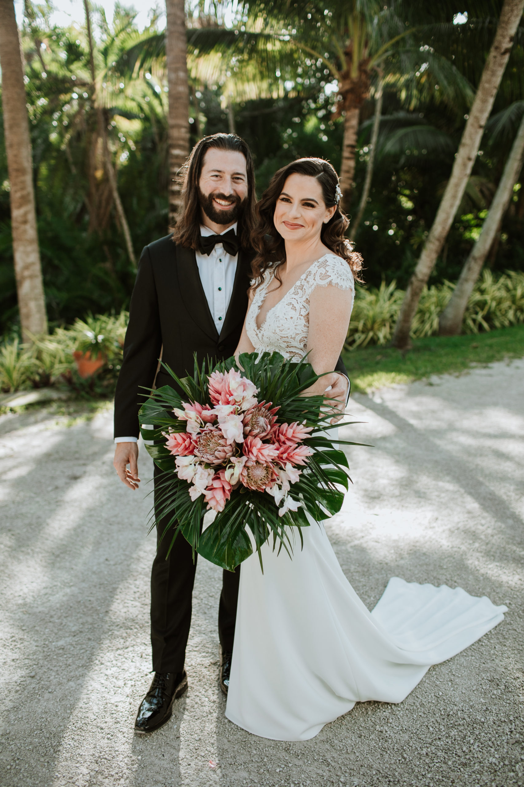 Lovely portrait of the bride and groom with the wedding bouquet outdoors at the Bonnet House Museum & Gardens, wedding planned by Oh My Occasions