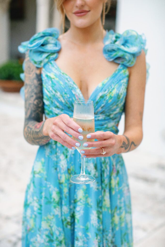 Someone came perfectly in line with our cocktail hour theme! Bright, blue, and beautiful! This lovely lady is holding a glass of champagne at Indian Creek Country Club planned by Oh My Occasions.