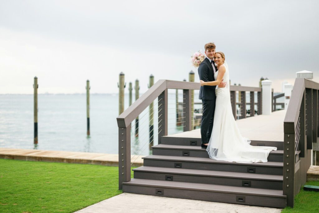 A stunning view of the water with the happy couple standing on top the bridge at Indian Creek Country Club planned by Oh My Occasions.