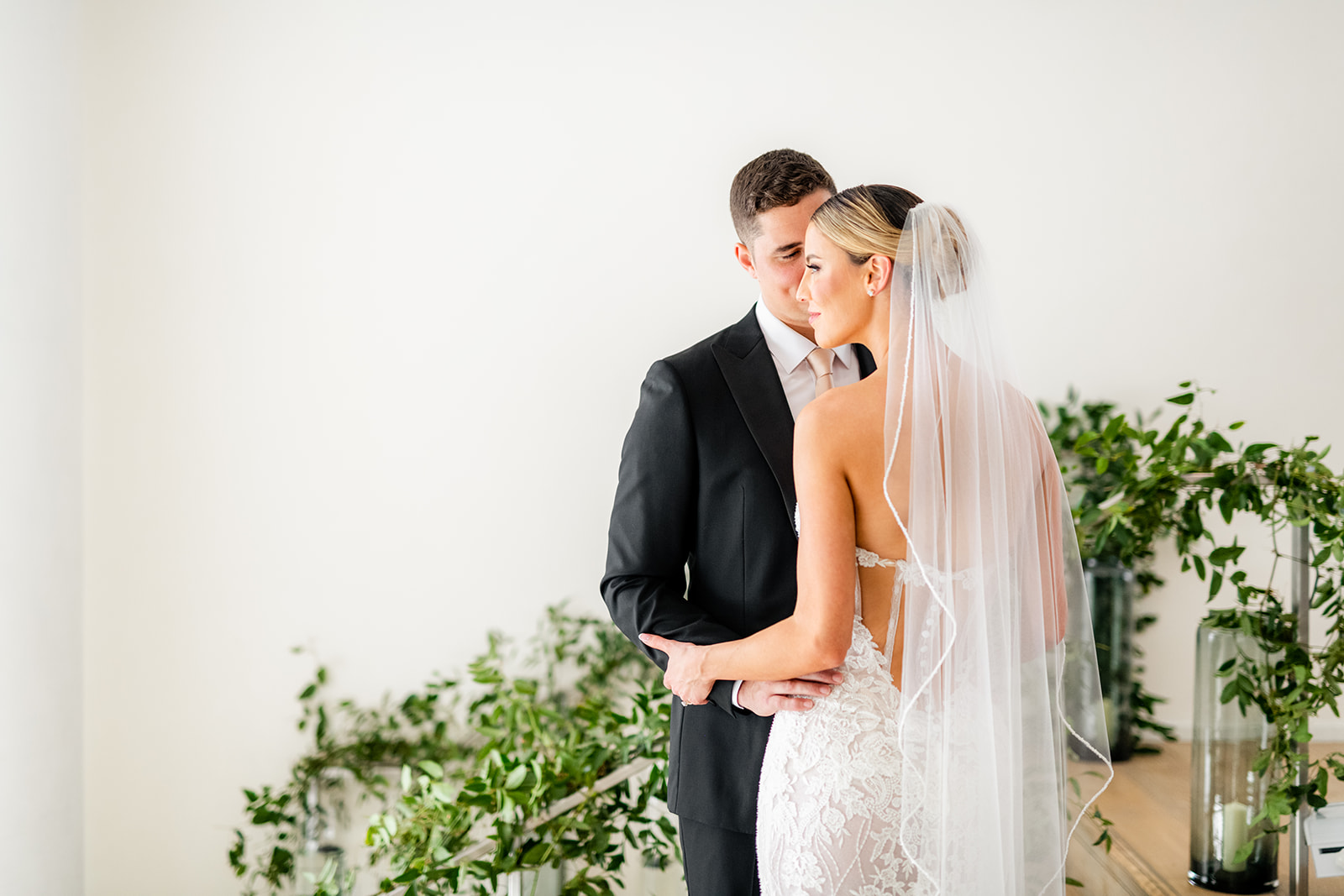 A still portrait of the bride and groom embracing each other with greenery behind them at Miami Beach Edition wedding, planned by Oh My Occasions