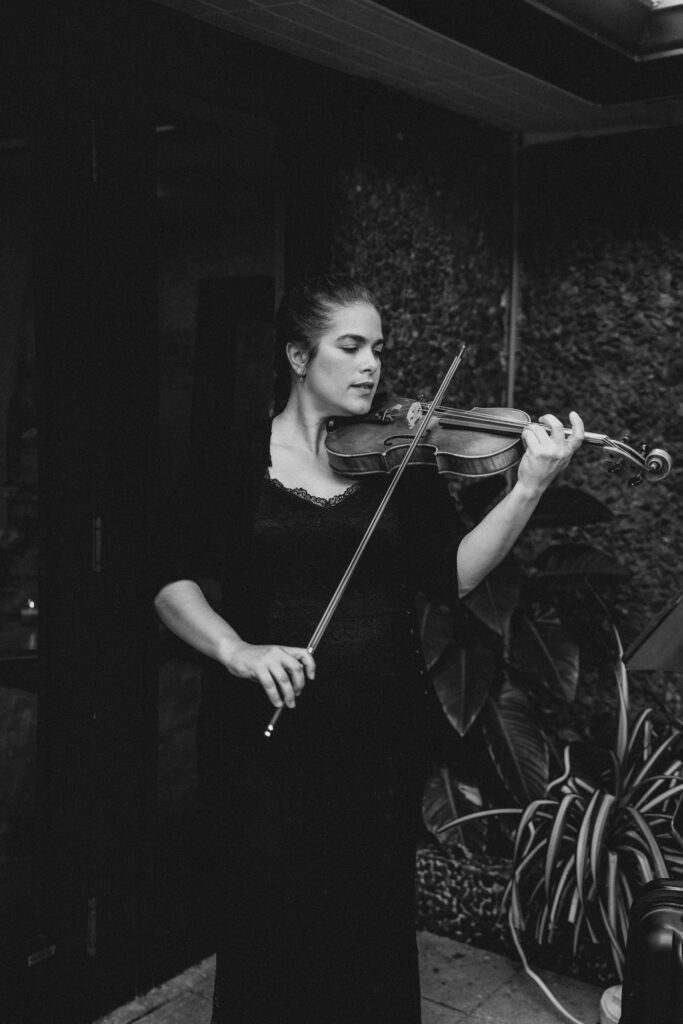 Black and white shot of the violinist playing at Live painter at Club of Knights wedding planned and designed by Oh My Occasions