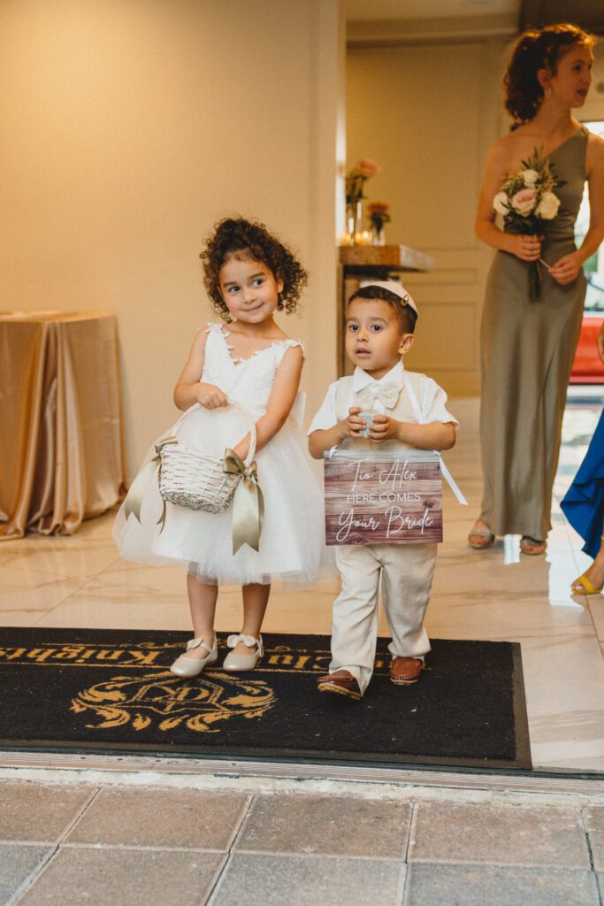 Cute flower girl and ring bearer posing together before walking down the aisle at Club of Knights wedding planned and designed by Oh My Occasions