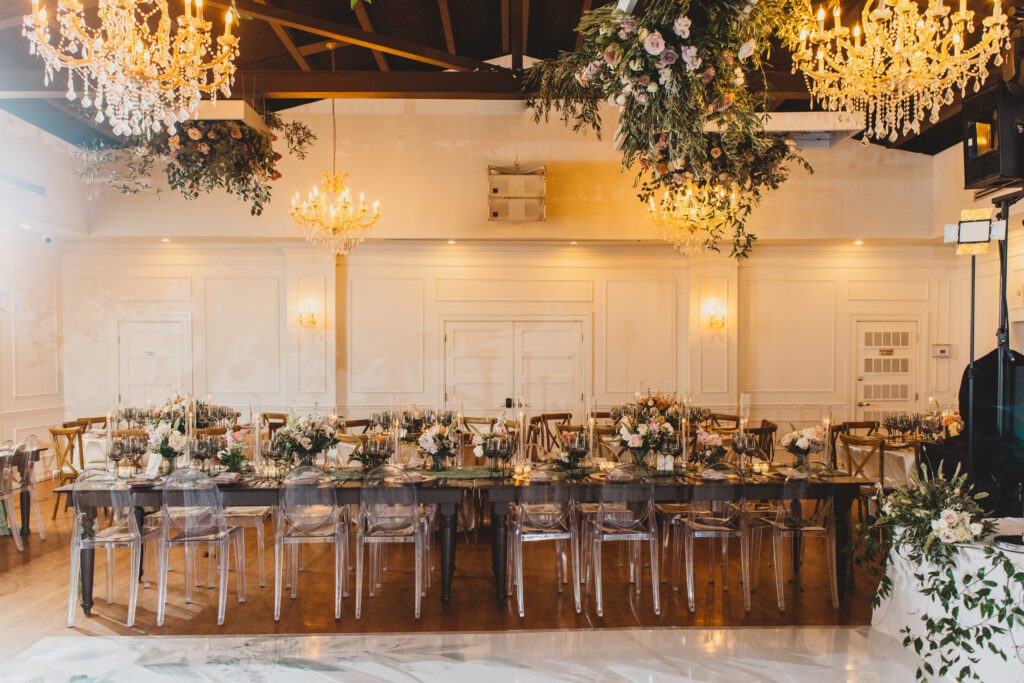 Fully set farm table with hanging floral arrangements and chandeliers at Club of Knights wedding planned and designed by Oh My Occasions