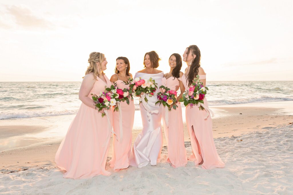 a bride and her bridesmaids take a photo on the beach at La Playa Golf and Beach Resort in Naples Florida
